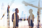 shadow of men shaking hands by construction cranes