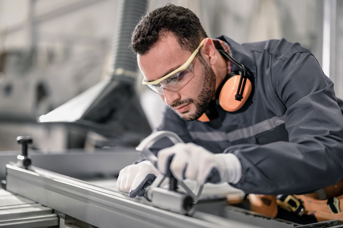 industrial-worker-using-saw-in-factory-workplace man working metal wearing safety goggles